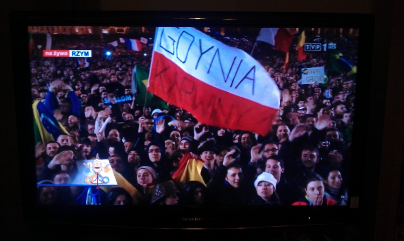 Polska flaga z napisem Gdynia Karwiny w programie 1 Telewizji Polskiej transmitującej wybór nowego papieża