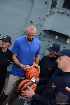 Marcin Gortat podpisuje piłkę na pokładzie ORP Generał Tadeusz Kościuszko, fot. Piotr Leoniak