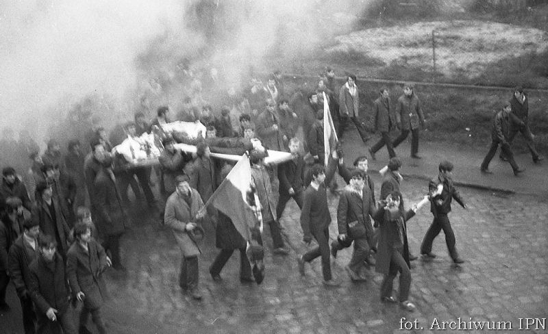 17 grudnia 1970 r. w Gdyni: robotnicy niosą na drzwiach ciało 18letniego Zbyszka Godlewskiego / fot. Archiwum IPN