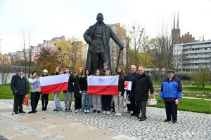 Prezydent Gdyni Wojciech Szczurek i radny Zenon Roda z mieszkańcami Gdyni, którzy trzymają biało-czerwone flagi, przed pomnikiem Piłsudskiego 