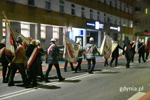 Osoby niosące sztandary idące po ulicy