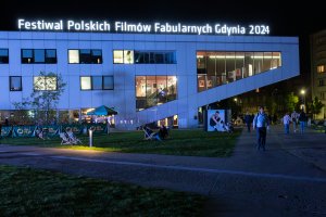 Wieczorny widok na Gdyńskie Centrum Filmowe i podświetlony na nim napis: Festiwal Polskich Filmów Fabularnych Gdynia 2024