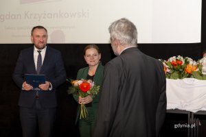 Mężczyzna i kobieta wręczają kwiaty i dyplom dla laureata konkursu