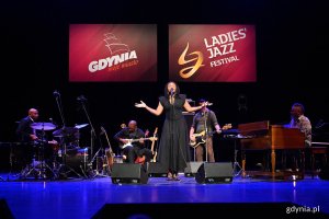 Lizz Wright na scenie, otoczona muzykami, u góry wyświetlają się napisy: "Gdynia moje miasto" oraz Ladies' Jazz Festival