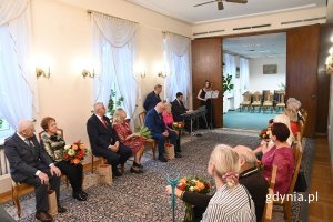 Grupa seniorów siedzących w eleganckiej sali