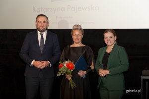 Laureat konkursu z kwiatami i dyplomem pozuje do zdjęcia z Prezydent Miasta Gdyni i dyrektorem zarządzającym 