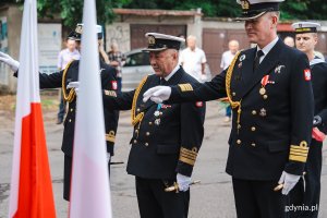 Mężczyźni w mundurach morskich lotników salutują.