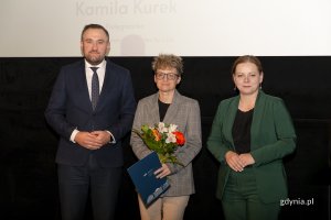 Laureat konkursu z kwiatami i dyplomem pozuje do zdjęcia z Prezydent Miasta Gdyni i dyrektorem zarządzającym 