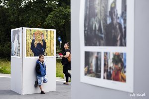 Ludzie oglądają plenerową wystawę fotografii.