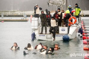 Uczestnicy projektu w strojach i kamizelkach z epoki wskakujący do wody z pokładu jachtu w gdyńskiej marinie