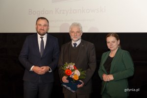 Laureat konkursu z kwiatami i dyplomem pozuje do zdjęcia z Prezydent Miasta Gdyni i dyrektorem zarządzającym 