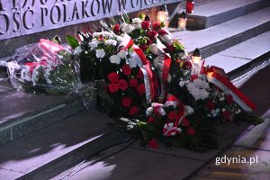 Biało-czerwone kwiaty złożone przed pomnikiem