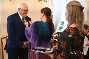 Prezydent Aleksandra Kosiorek przypinająca medal elegancko ubranemu seniorowi