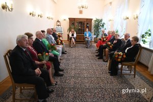 Grupa seniorów siedzących w eleganckiej sali