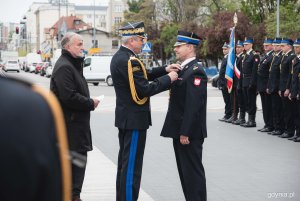 Nadbrygadier PSP przypina strażakowi odznaczenie.