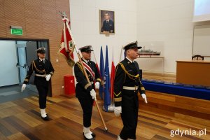 Poczet sztandarowy wchodzi do auli biblioteki AMW