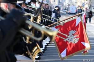 Żołnierze ustawieni w rzędzie, orkiestra i sztandar podczas uroczystości z okazji 99. rocznicy nadania Gdyni praw miejskich