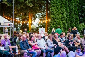 Publiczność zgromadzona na dziedzińcu Państwowego Liceum Sztuk Plastycznych im. Magdaleny Abakanowicz w Gdyni przed pokazem spektaklu  „Very Sad” w ramach pociągu „Pociąg do Miasta” 