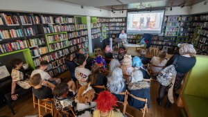 Panel dyskusyjny, w sali biblioteki siedzi prowadzący i słuchacze