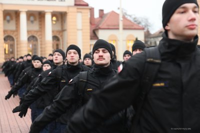 Plac między budynkami Akademii Marynarki Wojennej w Gdyni, studenci w granatowych mundurach maszerują w szeregu