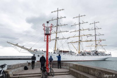 Falochron, nabrzeże, ludzie na nabrzeżu robią zdjęcia, Dar Młodzieży wpływa do portu