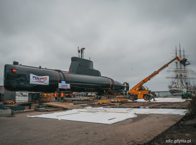 trwające przygotowania łodzi podwodnej do transportu, widoczna łódź podwodna, dźwig, trwające prace