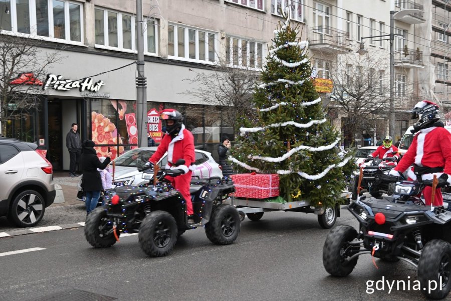 Motocykliści przebrani za mikołaje jadą ulicą Świętojańską i mają na przyczepie choinkę