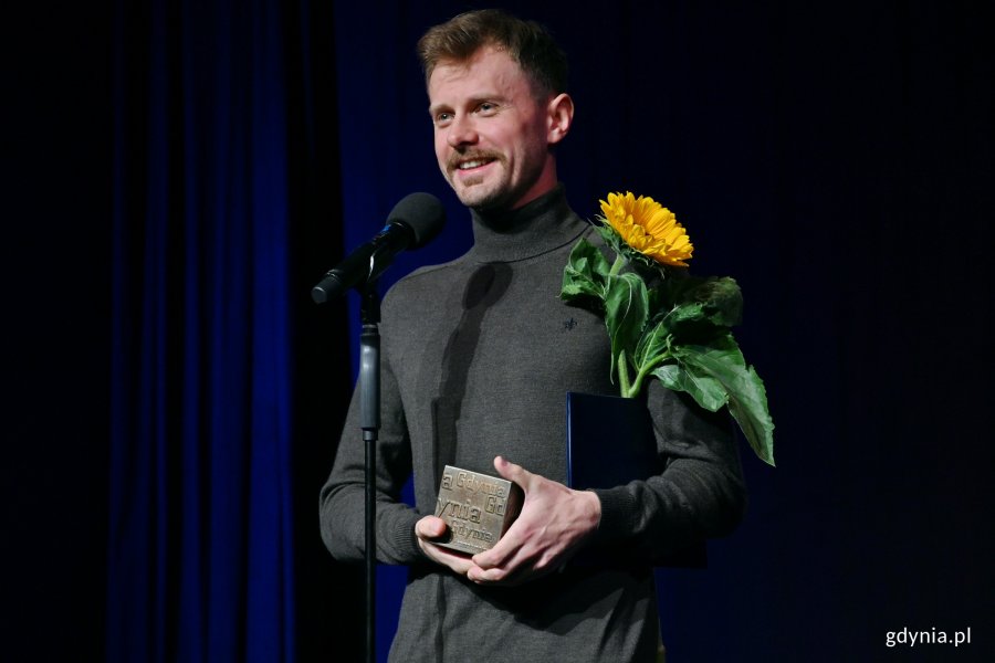 Radosław Maciąg, laureat 17. edycji konkursu o Gdyńską Nagrodę Dramaturgiczną, ze statuetką i kwiatem słonecznika