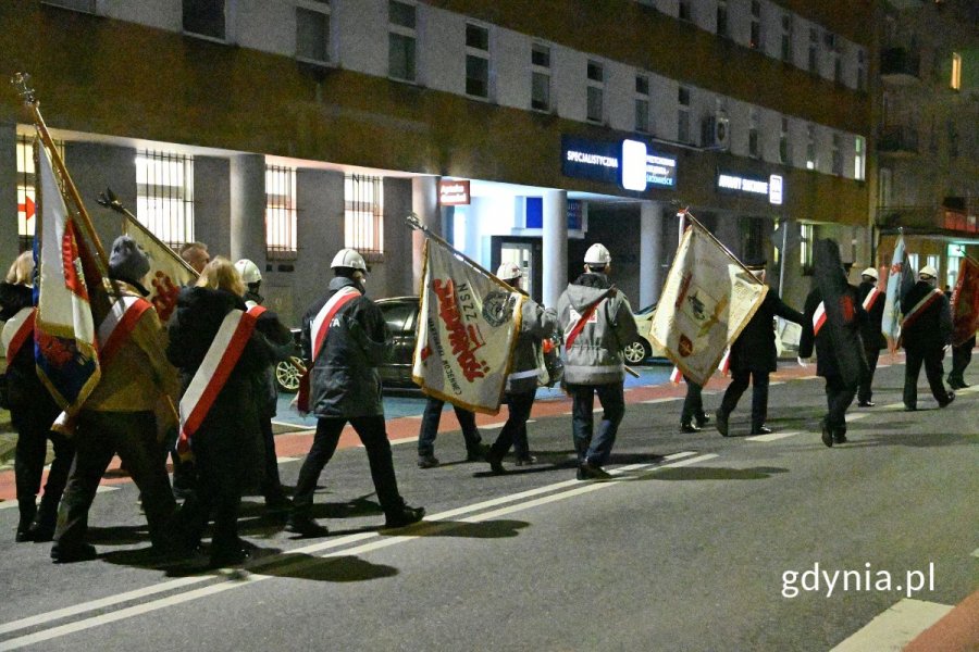 Osoby niosące sztandary idące po ulicy