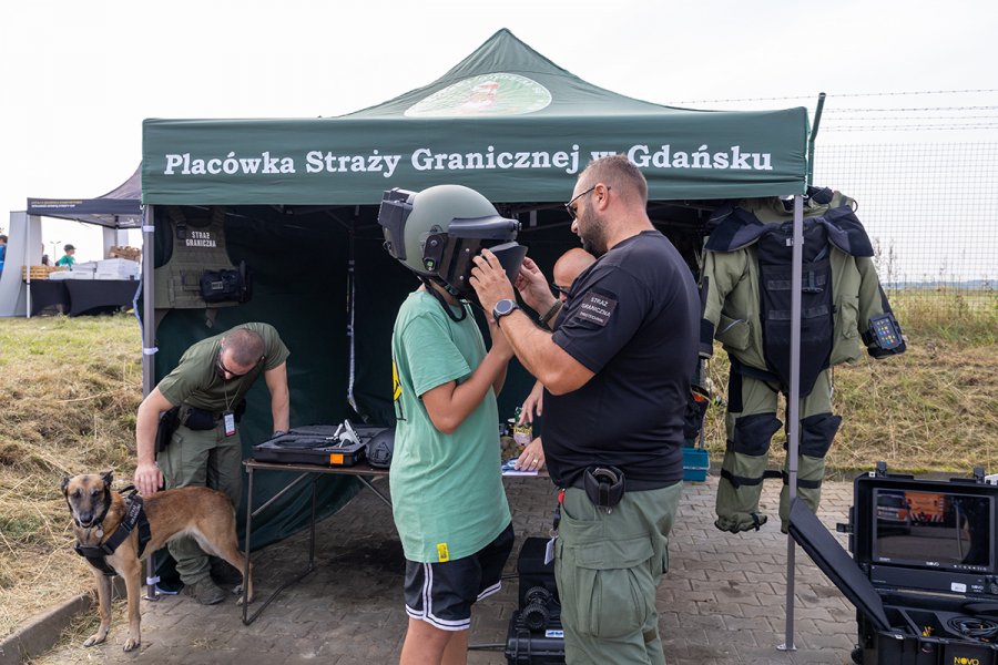 Dziecko przy pomocy umundurowanego mężczyzny zakłada kask