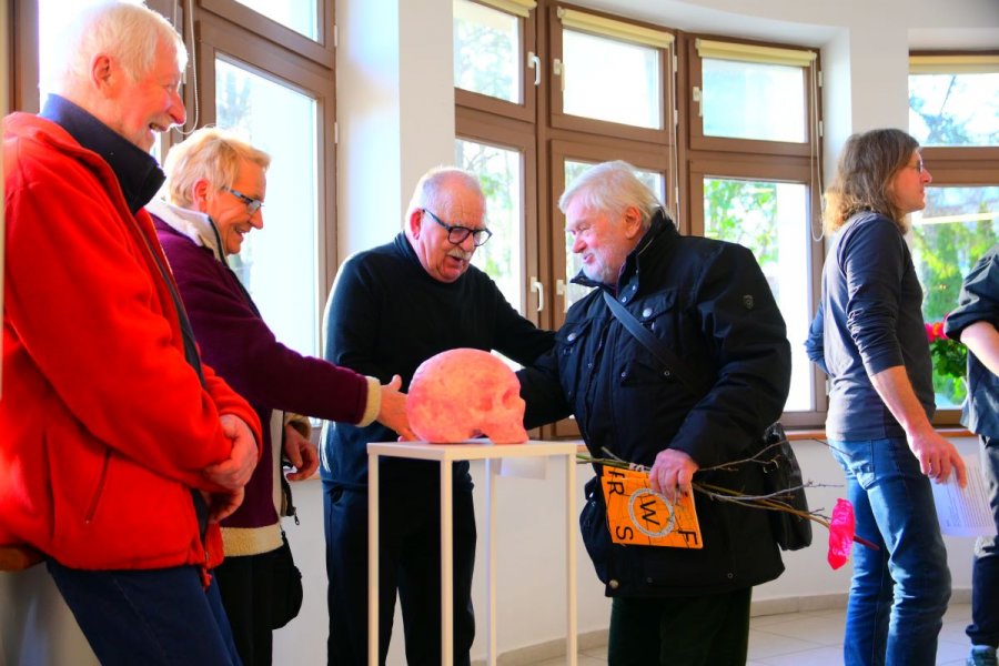 Czterech starszych panów podziwia pomarańczową czaszkę