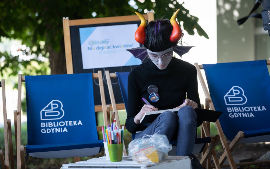 Uczestniczka Minicon-chan „Tanabata” w przebraniu na leżaku z napisem Biblioteka Gdynia