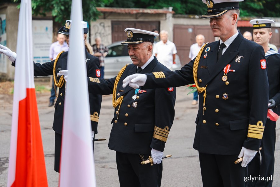 Mężczyźni w mundurach morskich lotników salutują.