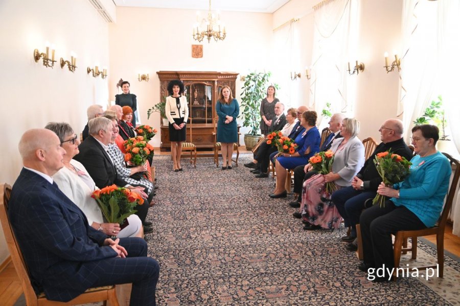 Seniorzy siedzący w eleganckiej sali