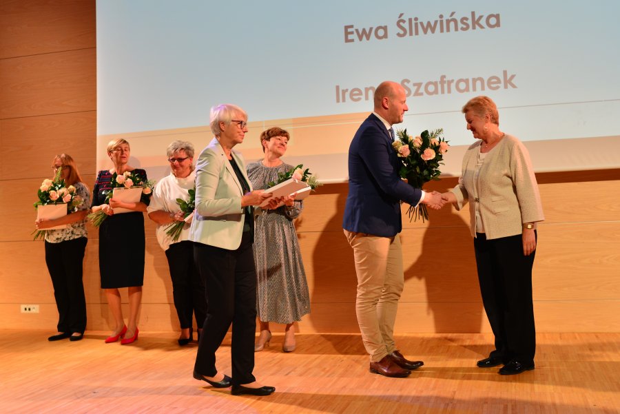 Na scenie wiceprezydent wręczający kwiaty, przewodnicząca rady z pamiątkowym prezentem