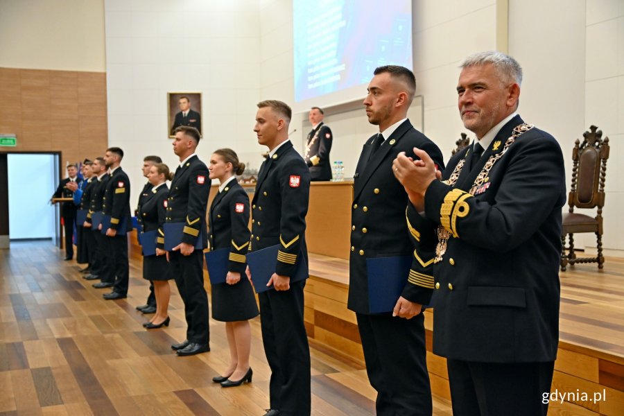 Absolwenci studiów II stopnia Akademii Marynarki Wojennej i rektor-komendant uczelni kadm. prof. dr hab. Tomasz Szubrycht podczas uroczystości wręczenia dyplomów