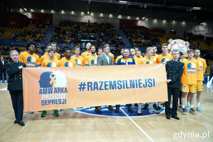 Zwodnicy AMW Arki, dyrektor Tomasz Augustyniak i prezes klubu Bartłomiej Wołoszyn przy banerze z napisem: AMW Arka przeciw depresji. #Razem silniejsi