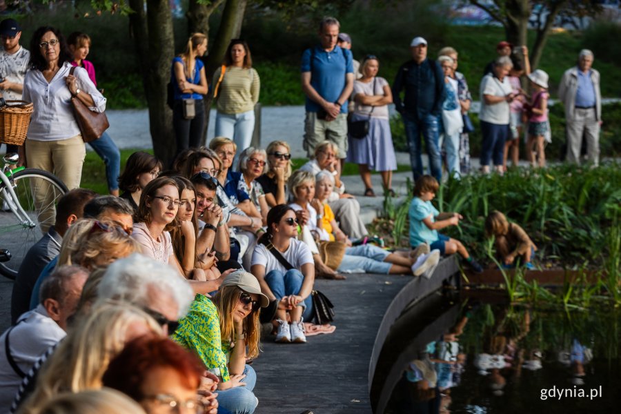 Ludzie siedzą nad stawem w parku.