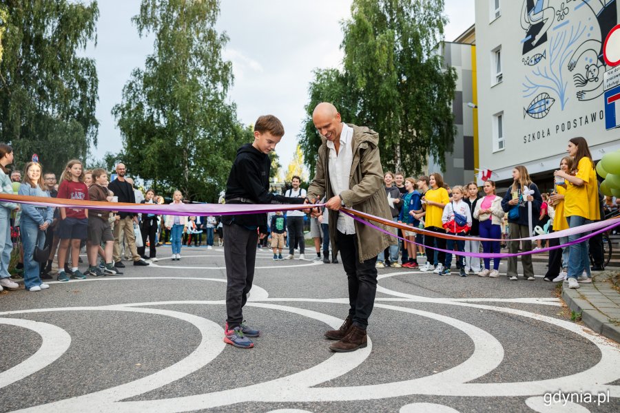 Adam Chyliński - inicjator projektu i placemaker wraz z jednym z uczniów przecinający wstęgę podczas oficjalnego otwarcia muralu i ulicy szkolnej na Hallera