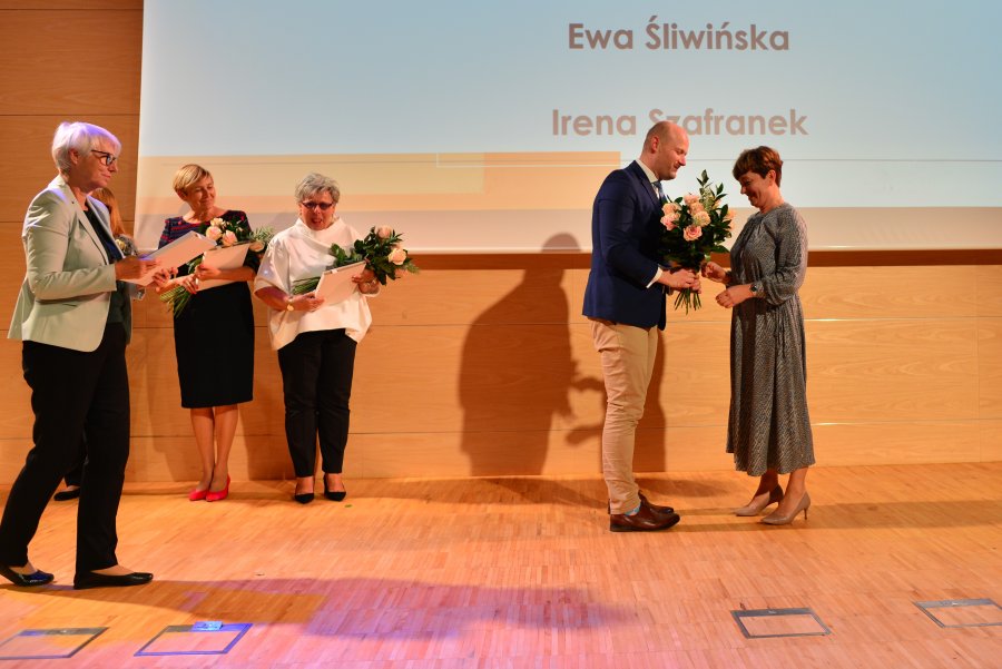 Na scenie wiceprezydent wręczający kwiaty, przewodnicząca rady z pamiątkowym prezentem