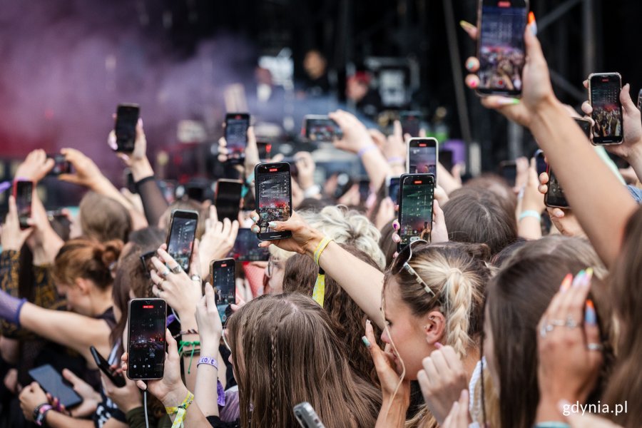 Tłum ludzi bawi się na Open'erze z telefonami w rękach