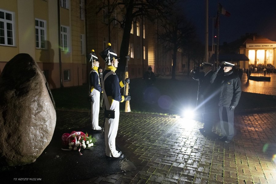 Podchorążowie w historycznych mundurach pełnia warte przed pomnikiem.