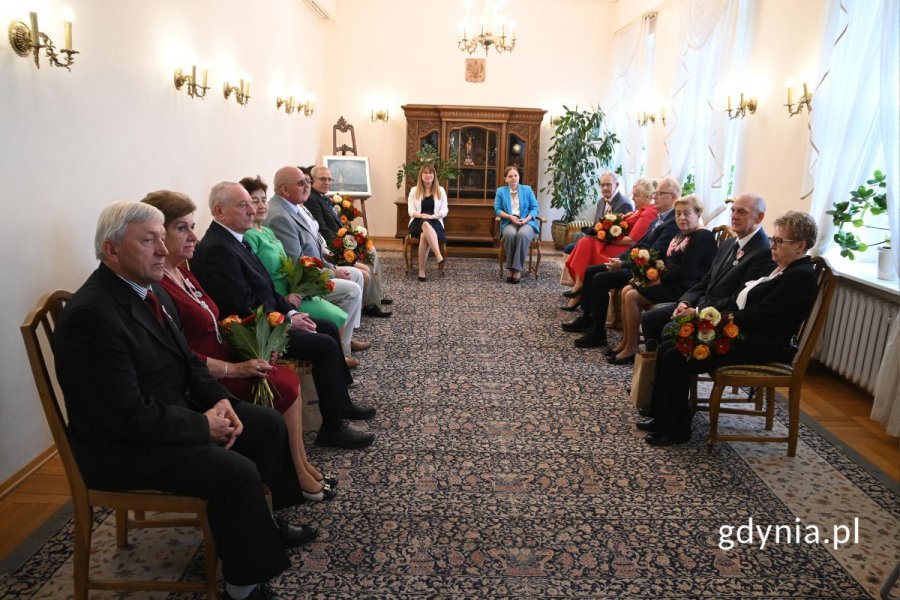 Grupa seniorów siedzących w eleganckiej sali