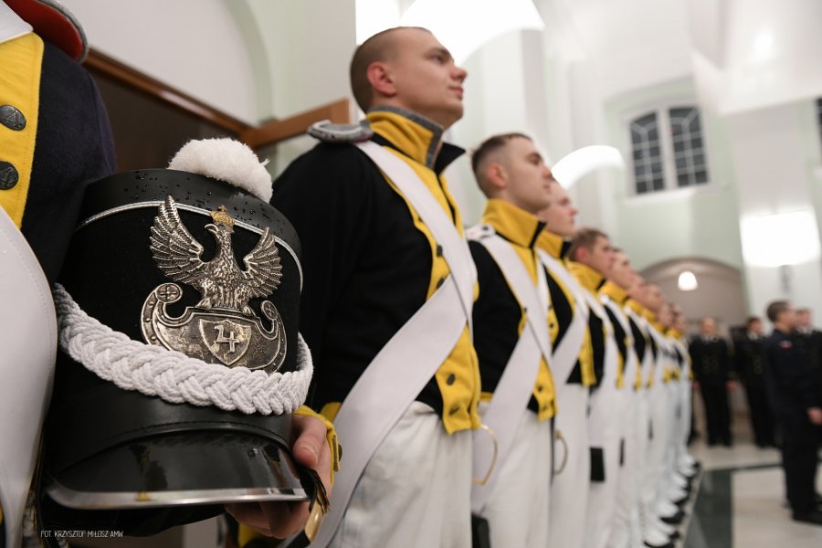 Rząd podchorążych w historycznych mundurach, na pierwszym planie czapka.