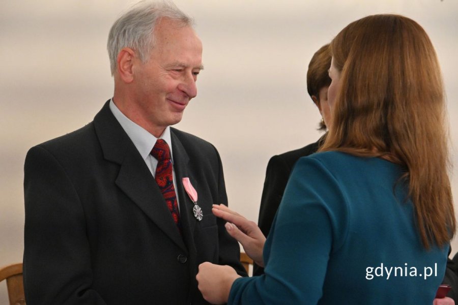 Aleksandra Kosiorek przypinająca seniorowi medal do klapy garnituru