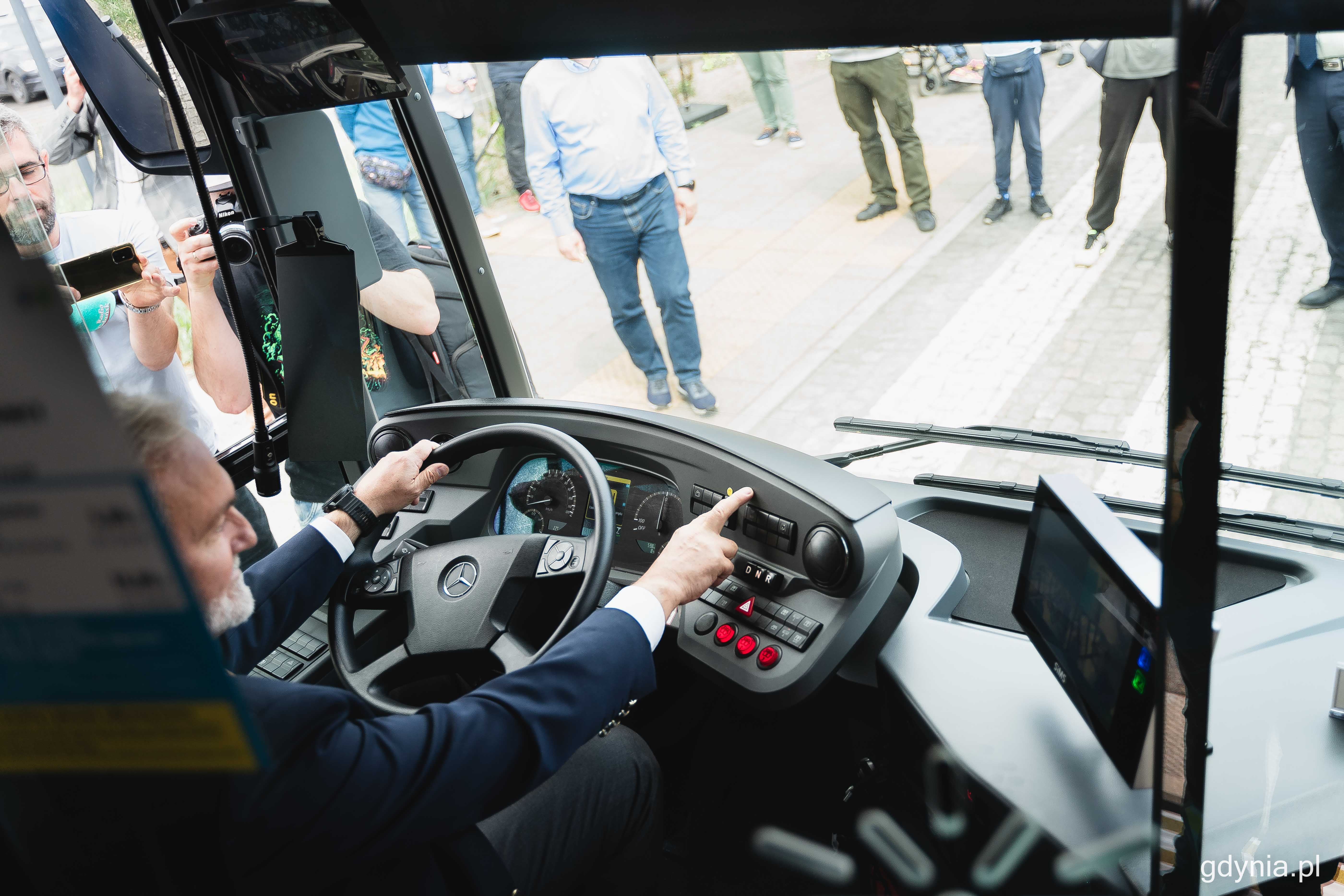 Prezydent Wojciech Szczurek naciska przycisk, który podłącza pantograf nowego elektrobusa do ładowarki, fot. Kamil Złoch