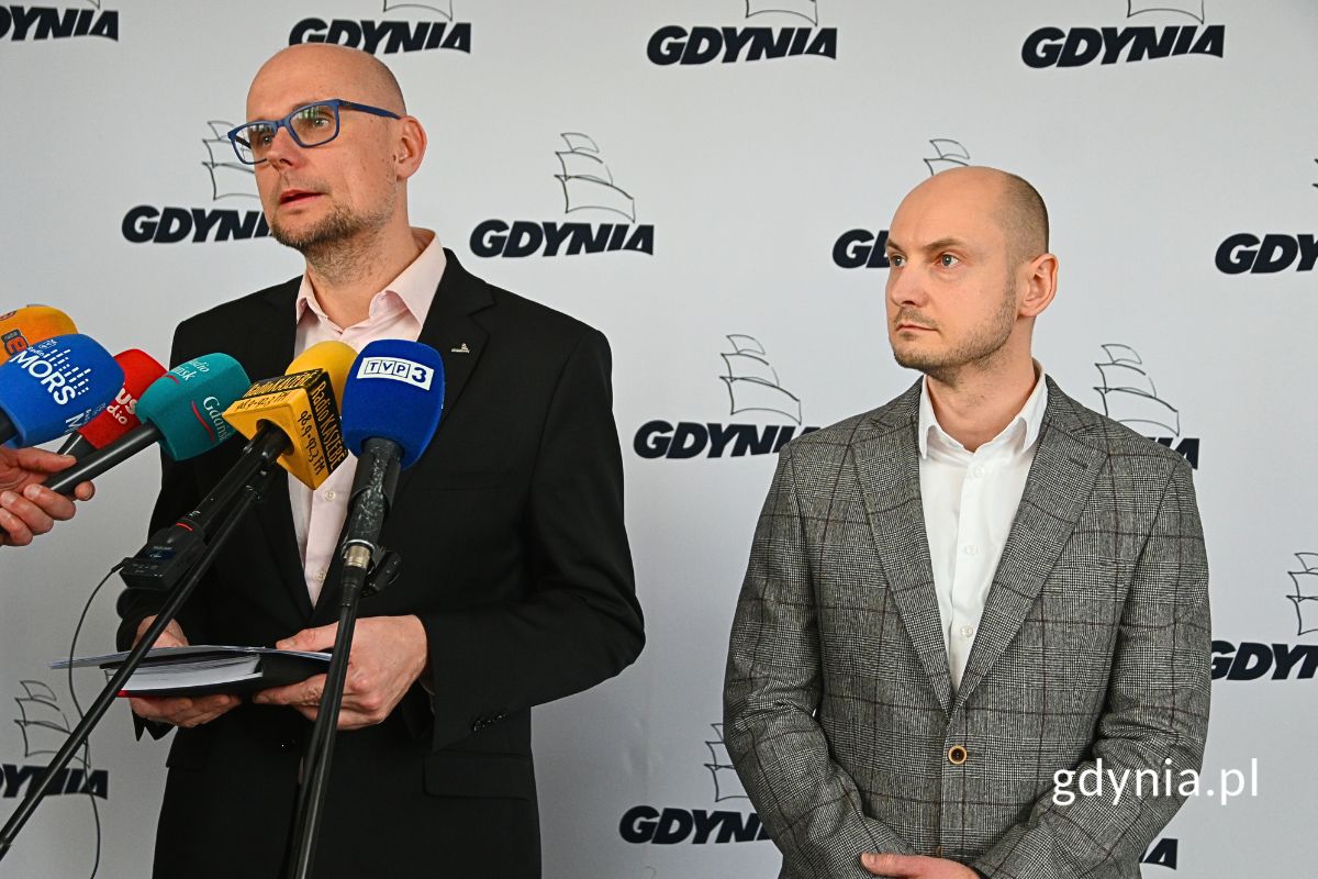 Bartłomiej Austen, wiceprezydent Gdyni oraz Adam Kisielewski, dyrektor kontraktu konsorcjum Polimex Mostostal S.A. i Polimex Infrastruktura sp. z o.o. stojący przed mikrofonami na tle ścianki z logotypami Gdyni