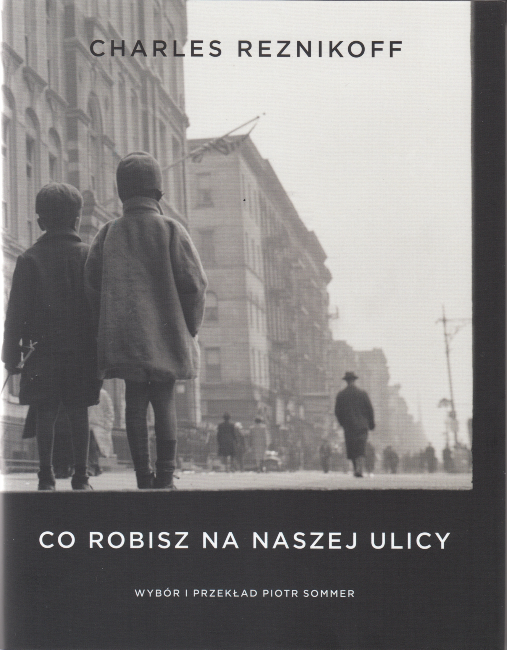 Okładka książki Charlesa Reznikoffa pt. "Co robisz na naszej ulicy". Na pierwszy planie dwójka małych dzieci stoi na ulicy. W tle wysokie budynki i inni przechodnie. U góry czarny napis z imieniem i nazwiskiem autora. Na dole białe napisy z tytułem książki oraz imieniem i nazwiskiem tłumacza // fot. materiały prasowe