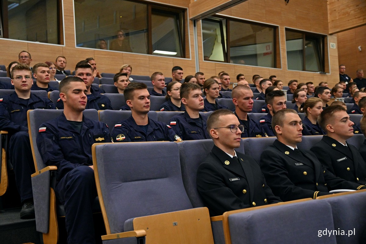 Sala w AMW, widownia, na krzesłach siedzą studenci w uniformach koloru granatowego