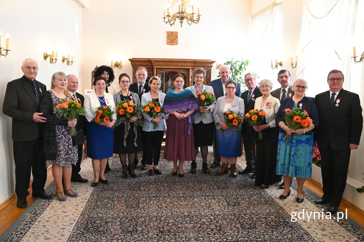 Grupa seniorów stojąca w rzędzie z prezydent Gdyni Aleksandrą Kosiorek